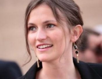 Person mit langen Ohrringen lächelt und blickt zur Seite.