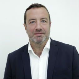 Person in einem Anzug vor neutralem Hintergrund.