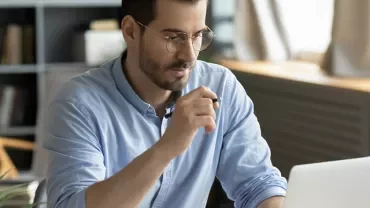 Person arbeitet am Laptop in einem modernen Büro.