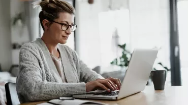 Person arbeitet an einem Laptop in einem Wohnzimmer.