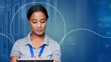 Person in einem Serverraum mit Tablet