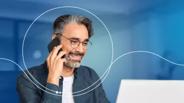 Person telefoniert und lächelt am Laptop.