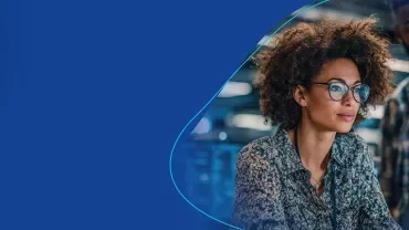 Frau arbeitet konzentriert an einem Laptop im modernen IT-Umfeld