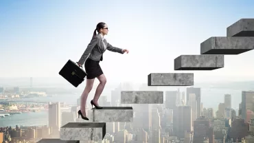 Person steigt eine Treppe hinauf mit einer Stadt im Hintergrund.