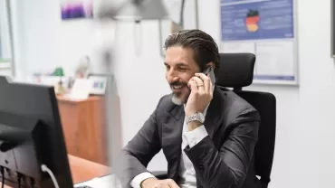 Person telefoniert im Büro und lächelt