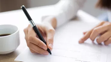 Person füllt ein Formular mit einem Stift aus.