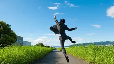 Person in Anzug springt auf einem Landweg.