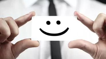 Eine Person hält eine Karte mit einem Smiley-Gesicht.