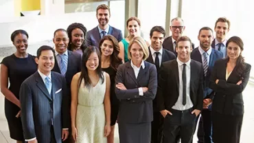 Gruppe von Menschen in Businesskleidung lächelt in die Kamera.