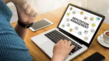 Person arbeitet an einem Laptop mit der Aufschrift 'Reputation Management'.
