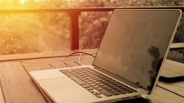 Laptop auf einem Holztisch bei Sonnenuntergang.