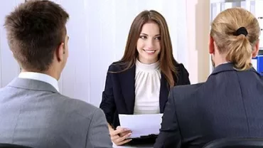 Person in Anzug bei einem Interview mit zwei anderen Personen.