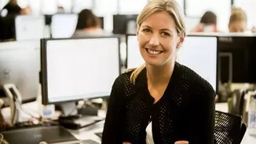 Lächelnde Person in einem Büro vor Computern.