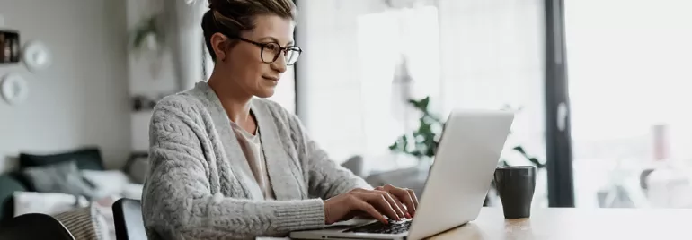 Person arbeitet an einem Laptop in einem Wohnzimmer.