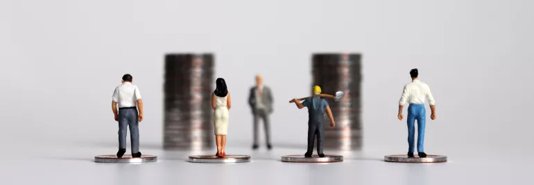 Miniaturfiguren stehen auf Münzen.