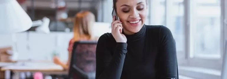 Person telefoniert in modernem Büro und macht Notizen.