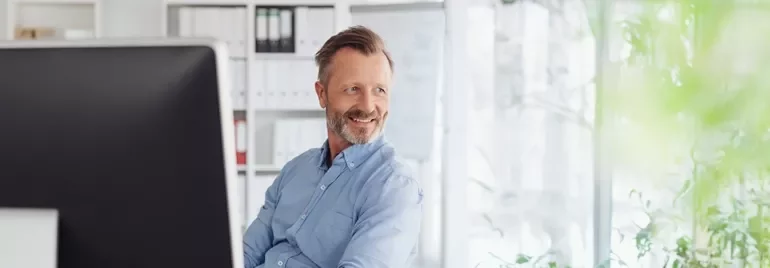 Person im Büro schaut über den Computerbildschirm.