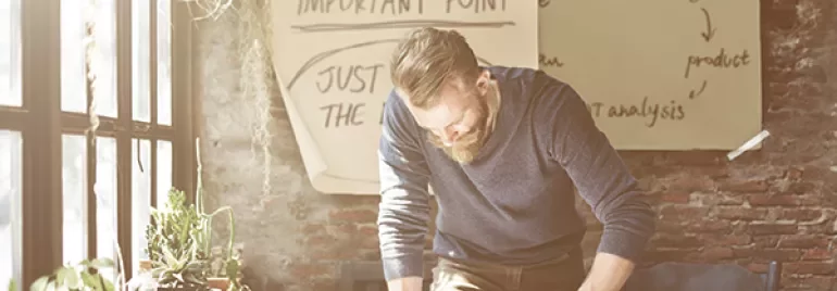 Person arbeitet an einem Tisch mit Pflanzen und Notizen.