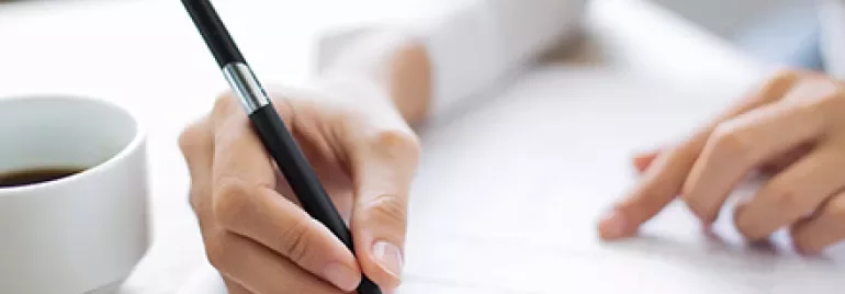 Person füllt ein Formular mit einem Stift aus.