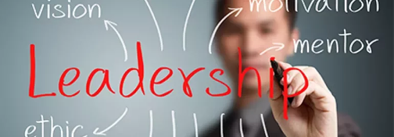 Eine Person schreibt das Wort 'Leadership' umgeben von Begriffen wie Vision und Verantwortung.