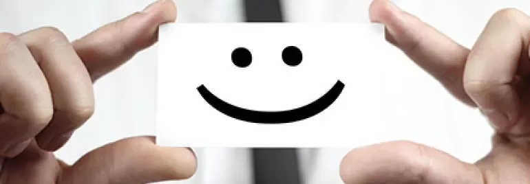 Eine Person hält eine Karte mit einem Smiley-Gesicht.