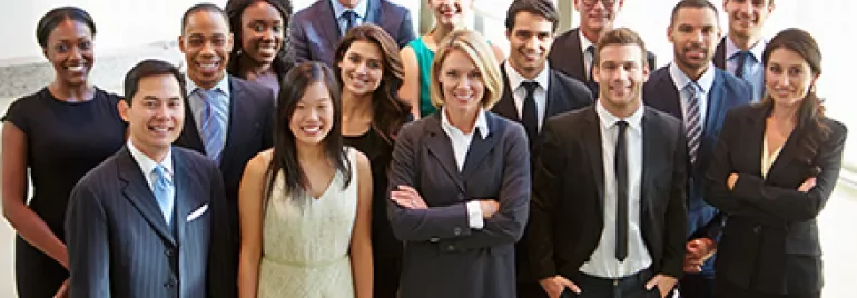 Gruppe von Menschen in Businesskleidung lächelt in die Kamera.
