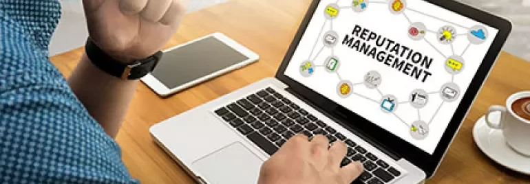 Person arbeitet an einem Laptop mit der Aufschrift 'Reputation Management'.
