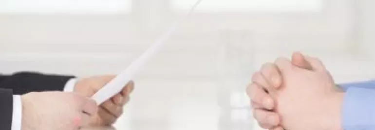 Zwei Personen sitzen am Tisch, die eine hält ein Papier.