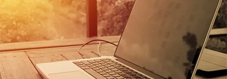 Laptop auf einem Holztisch bei Sonnenuntergang.