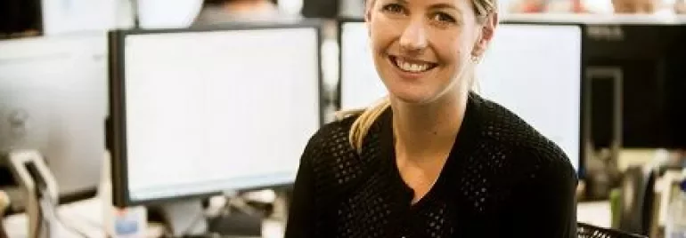 Lächelnde Person in einem Büro vor Computern.