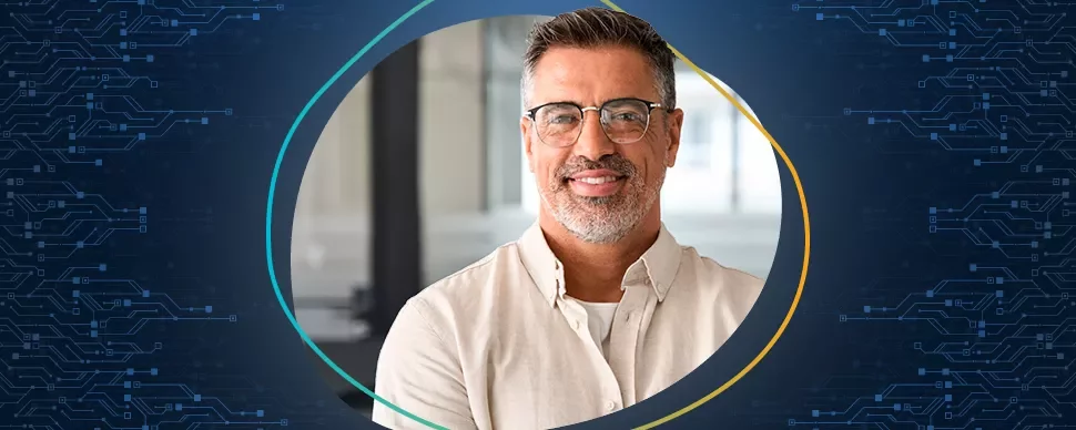 Person mit Brille und Bart lächelt vor einem technischen Hintergrund.