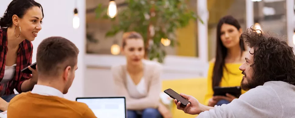 Gruppe von Menschen in einem Gespräch mit Laptops und Smartphones.