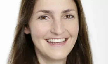 Porträt einer Person mit langem Haar und freundlichem Lächeln.