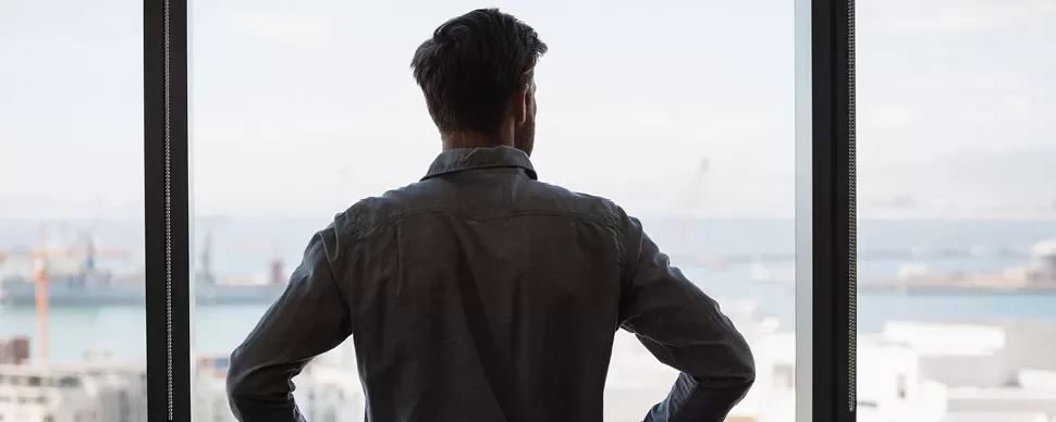 Person schaut aus einem Fenster auf einen Hafen.