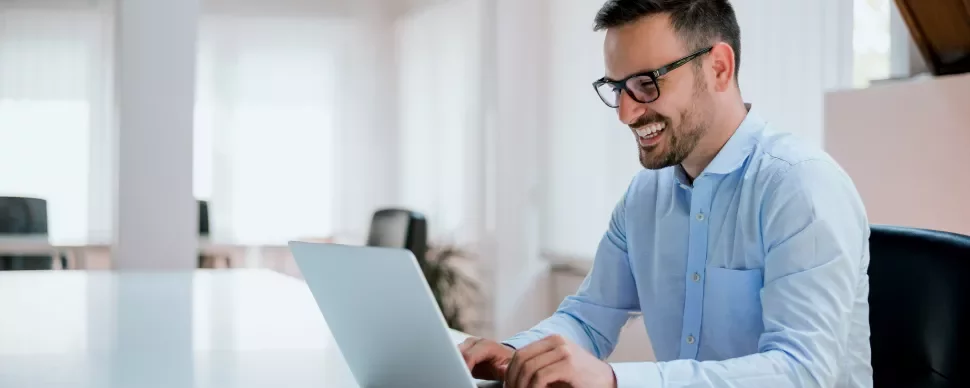 Lächelnde Person am Laptop in einem modernen Büro.