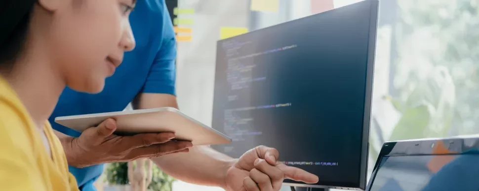 Zwei Personen arbeiten gemeinsam an einem Computerbildschirm.