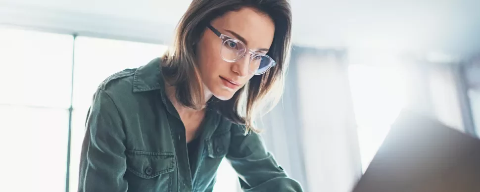 Person mit Brille arbeitet konzentriert an einem Laptop.