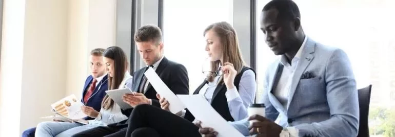 Gruppe von Menschen beim Lesen von Dokumenten im Büro.