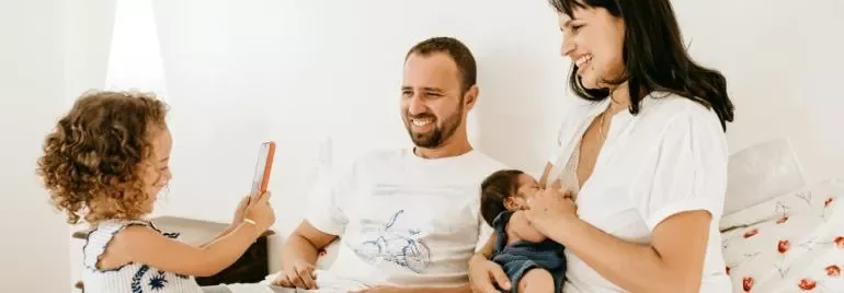Eine Familie lächelt und verbringt Zeit miteinander auf dem Bett.