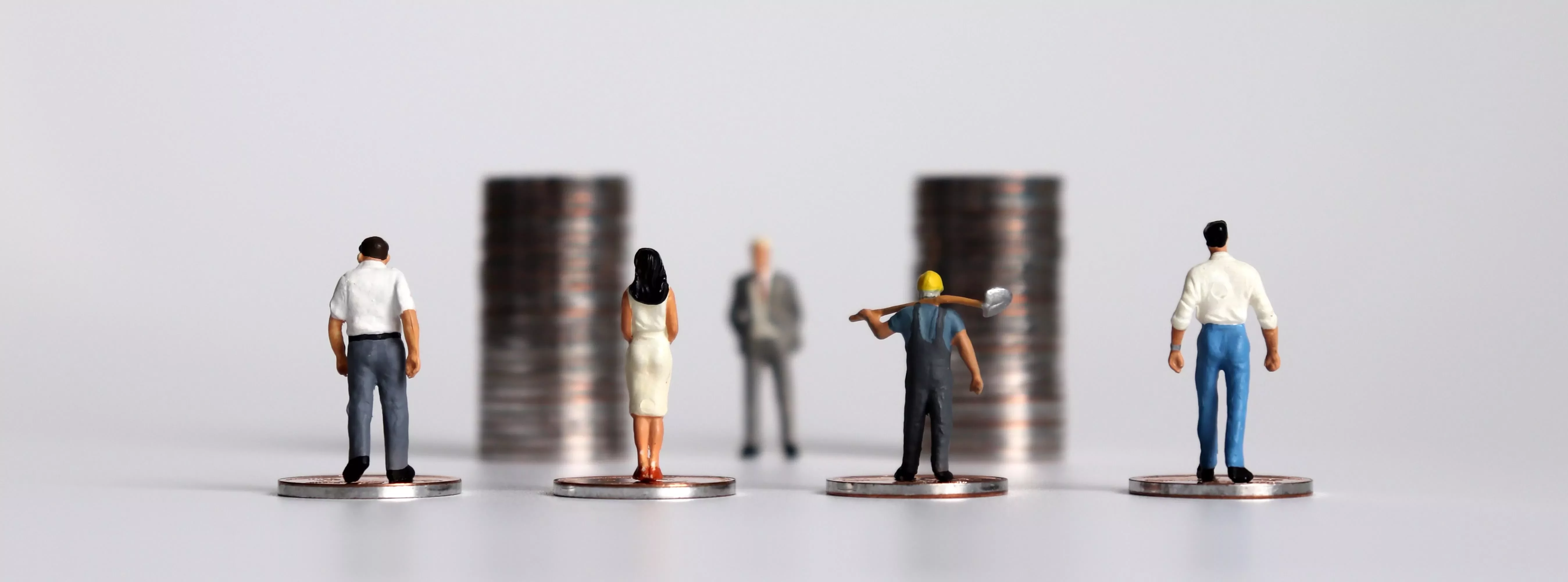 Miniaturfiguren stehen auf Münzen.