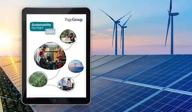 Tablet mit Nachhaltigkeitsbroschüre 2023, Solarzellen und Windkraftanlagen im Hintergrund.