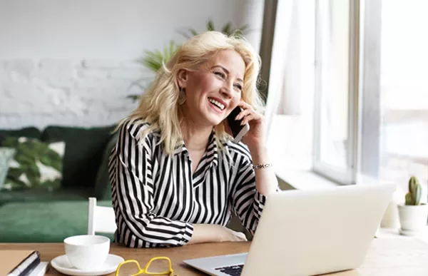 Person lächelt beim Telefonieren am Laptop