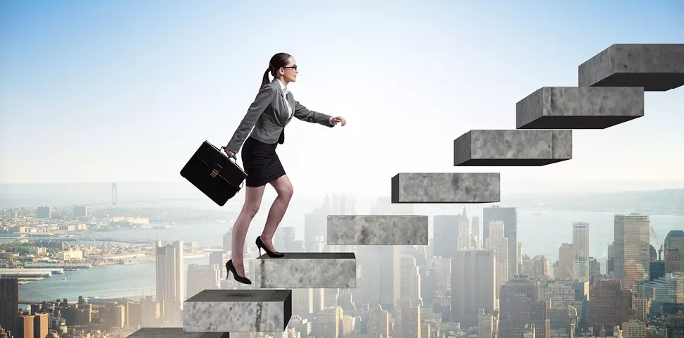 Person steigt eine Treppe hinauf mit einer Stadt im Hintergrund.