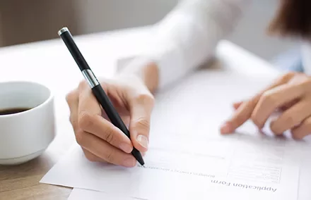 Person füllt ein Formular mit einem Stift aus.