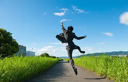Person in Anzug springt auf einem Landweg.