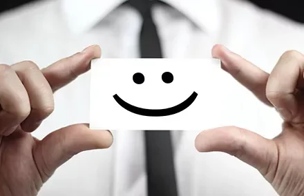 Eine Person hält eine Karte mit einem Smiley-Gesicht.
