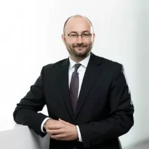 Person in Anzug lehnt an einem weißen Geländer.