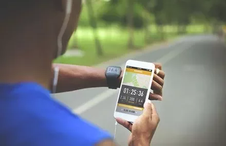 Person mit Handy und Smartwatch auf einer Straße.